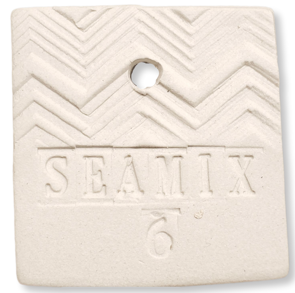 Square ceramic test tile made out of Happycozygoods Sea Mix 6 pottery clay, with zigzag pattern with 'SEAMIX 6' stamped on it, on a white background. 