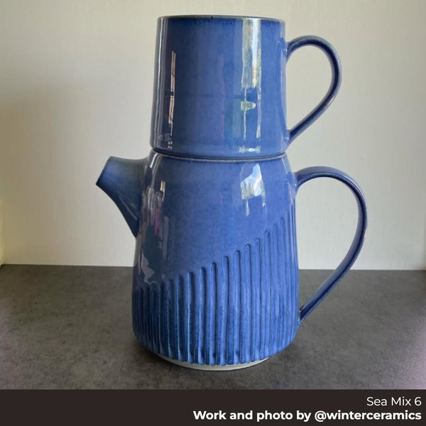 Blue ceramic pitcher with ribbed design on a gray surface. Made with Happycozygoods Sea Mix 6 clay